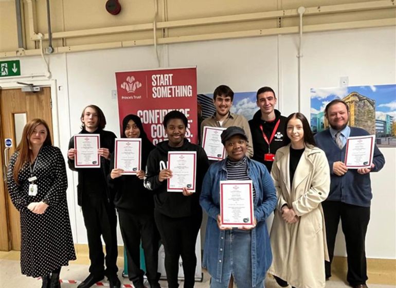 A group of young people holding certificates, standing together with Marks & Spencer staff and a representative from The Prince's Trust after completing a training programme.