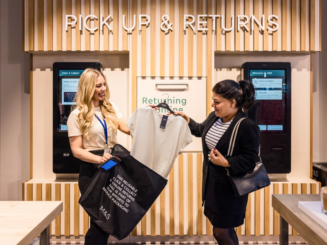 An employee assisting a customer with a clothing return at the 'Pick Up & Returns' station in a Marks & Spencer store.