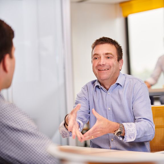 Two people in a discussion across a table, in an office setting.