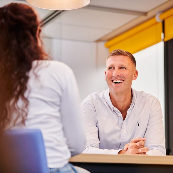 Two cheerful individuals collaborating at a table in a bright office space.