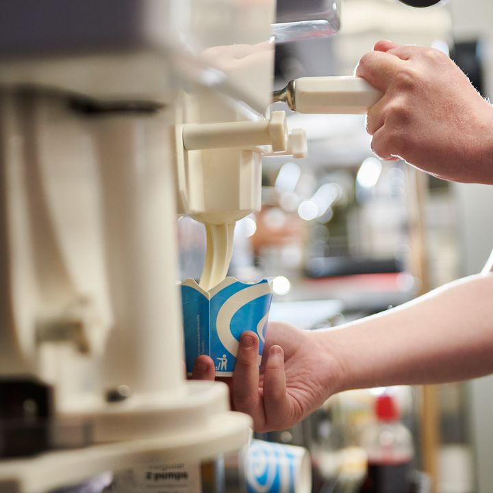 Close-up of a hand operating an ice-cream machine.