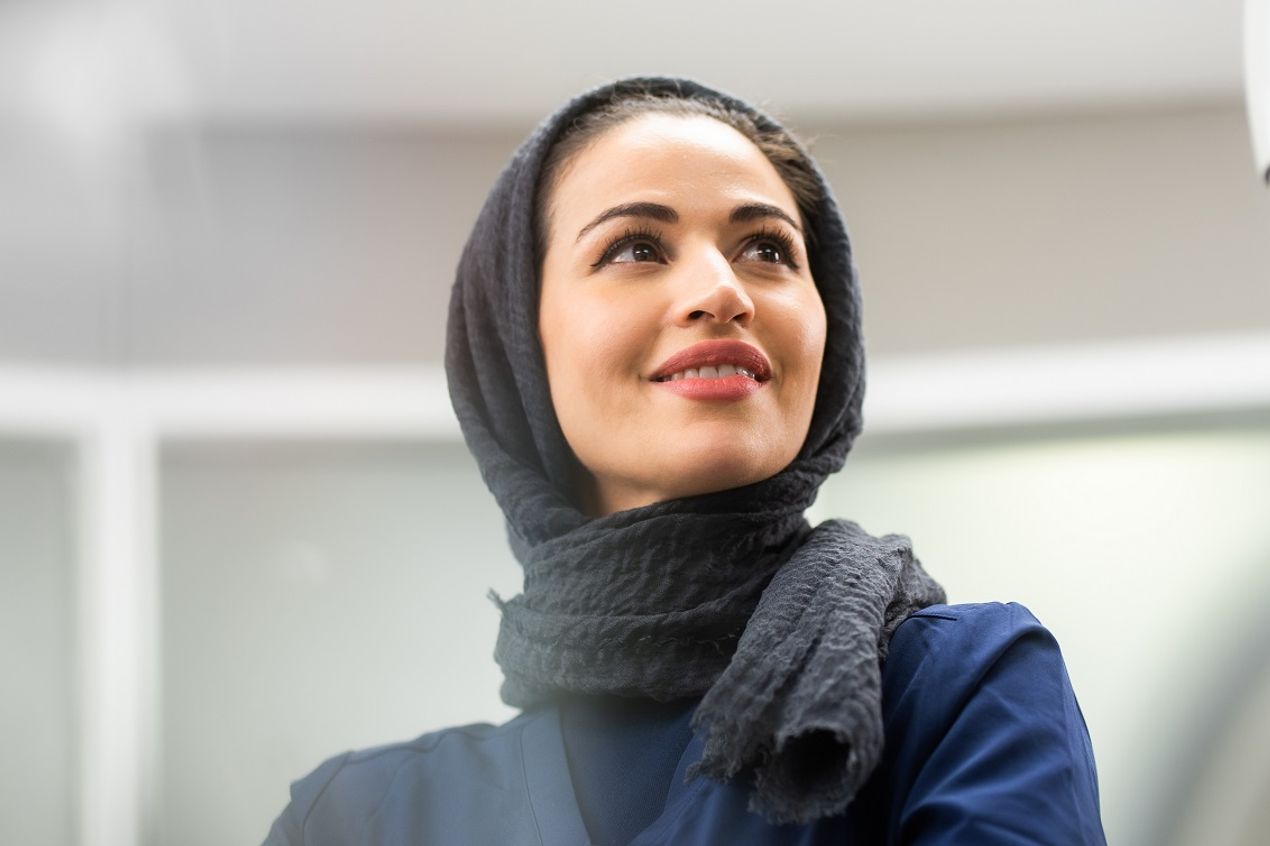 A Bupa healthcare professional in clinical uniform and headscarf, working in a clean, modern healthcare setting that supports patient care