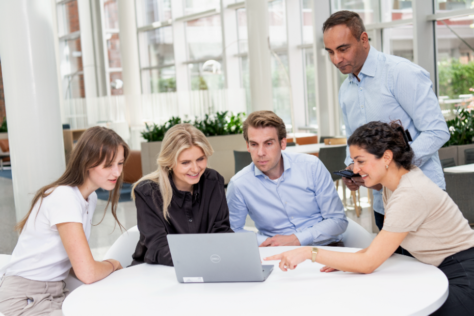 people in office surrounding a laptop