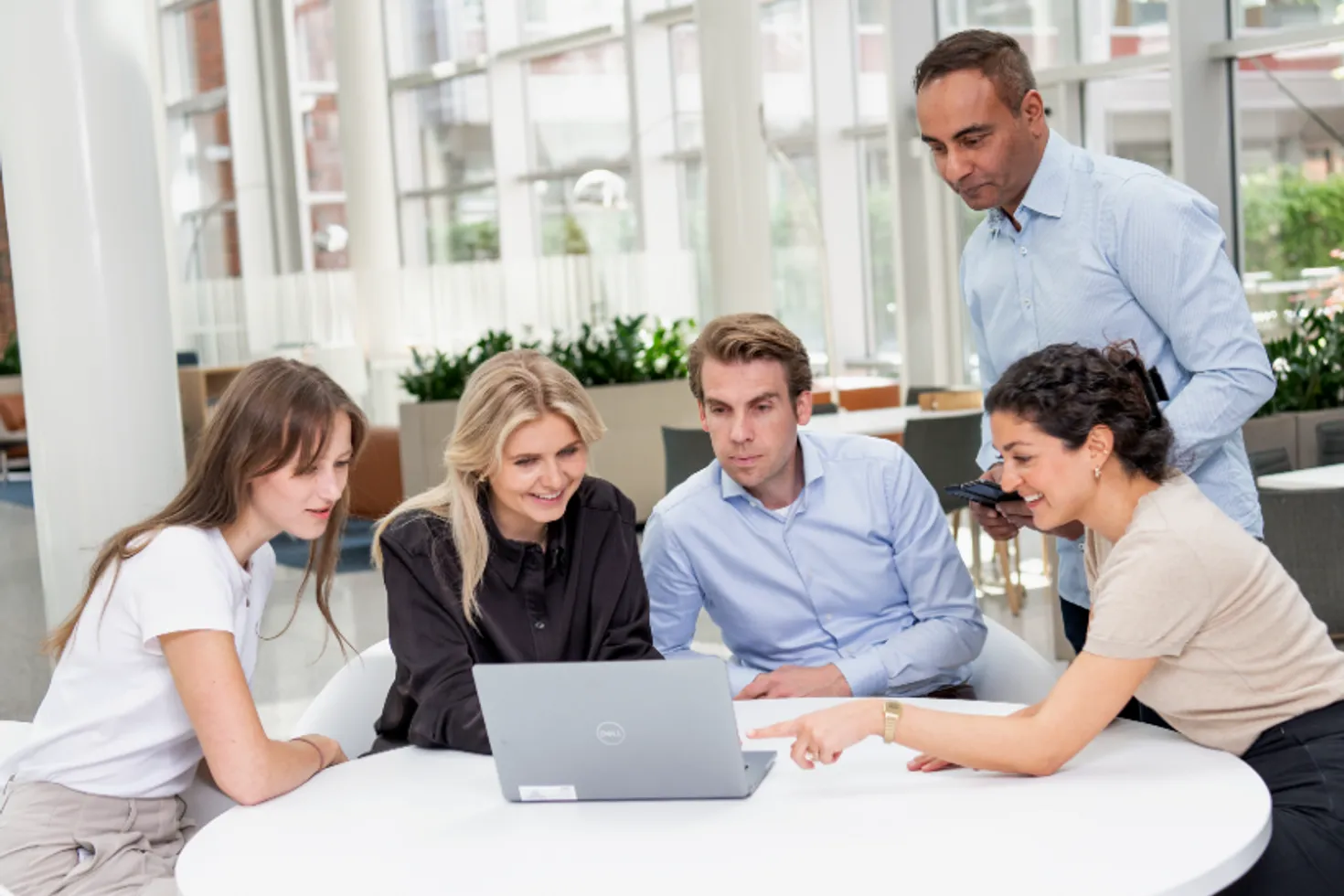 people in office surrounding a laptop